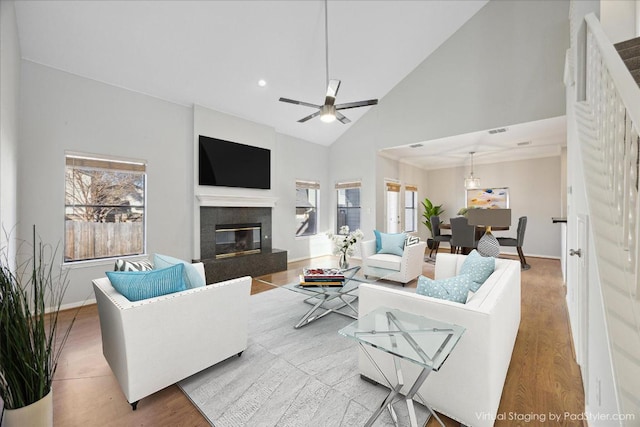 living room with a glass covered fireplace, high vaulted ceiling, baseboards, and wood finished floors