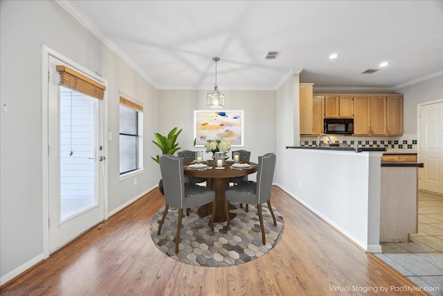 dining room with visible vents, light wood finished floors, and ornamental molding