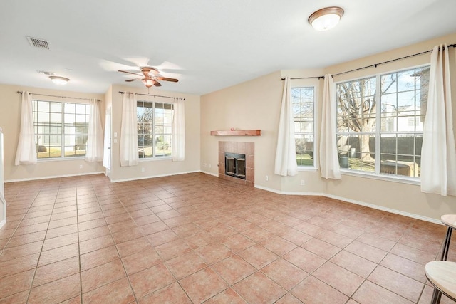 unfurnished living room with baseboards, a ceiling fan, light tile patterned floors, and a tile fireplace