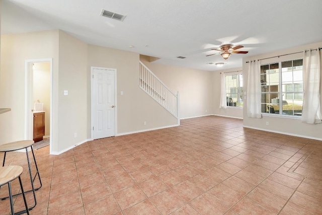 spare room with a ceiling fan, baseboards, visible vents, light tile patterned flooring, and stairs