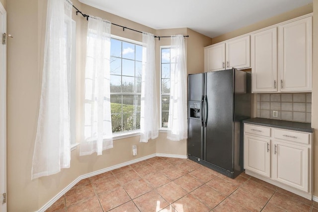 kitchen featuring tasteful backsplash, black fridge with ice dispenser, dark countertops, white cabinetry, and light tile patterned floors