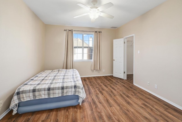 bedroom with a ceiling fan, wood finished floors, visible vents, and baseboards