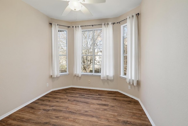 empty room featuring baseboards, dark wood-style floors, and a ceiling fan