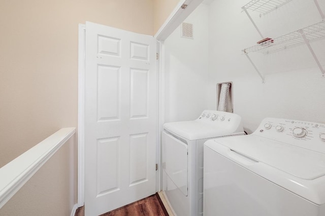 laundry room featuring dark wood finished floors, visible vents, washing machine and dryer, and laundry area