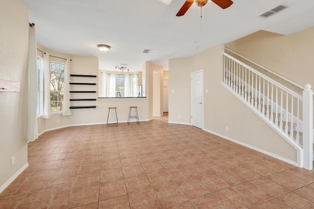 unfurnished living room featuring stairway, baseboards, visible vents, and ceiling fan