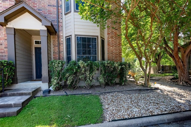 view of exterior entry with brick siding and fence