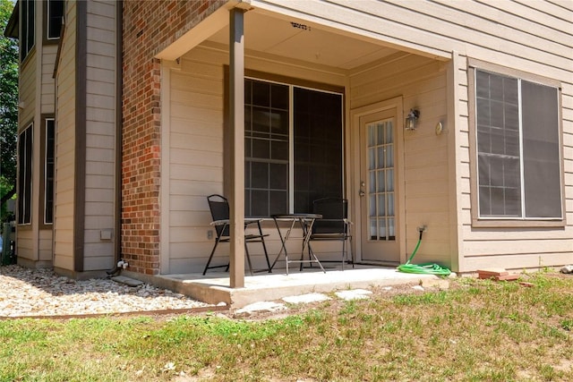property entrance featuring brick siding and a patio area