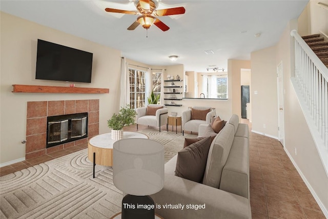 living area featuring ceiling fan, tile patterned flooring, stairway, and a fireplace