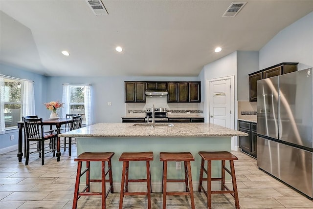 kitchen featuring a sink, visible vents, a breakfast bar, and freestanding refrigerator