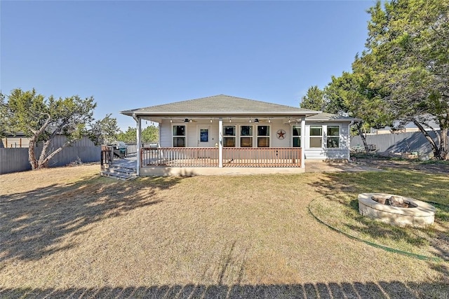 rear view of property with a fire pit, a lawn, a ceiling fan, and fence