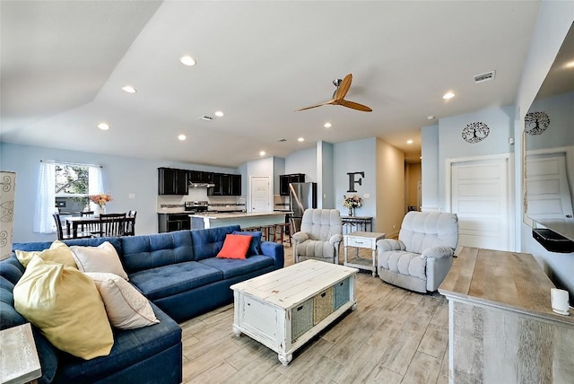 living room with vaulted ceiling, recessed lighting, light wood-style floors, and visible vents