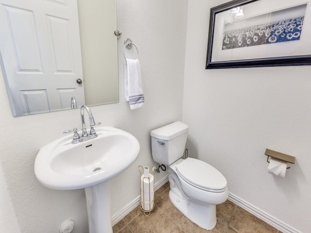 bathroom featuring tile patterned floors, baseboards, toilet, and a sink