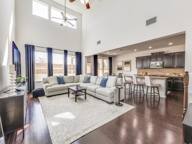 living area featuring dark wood-style floors, visible vents, and ceiling fan