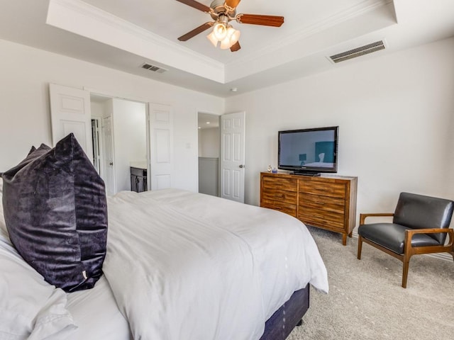 bedroom featuring visible vents, a raised ceiling, light carpet, and ornamental molding