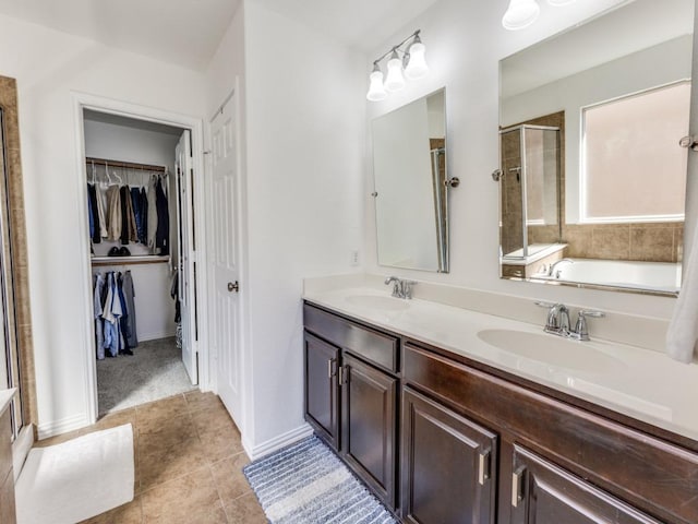 full bath with tile patterned floors, a spacious closet, a stall shower, and a sink