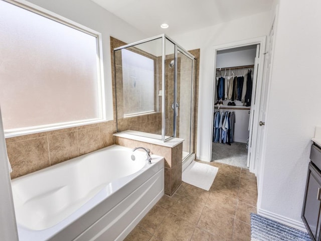 full bath with a spacious closet, tile patterned floors, a stall shower, a bath, and vanity