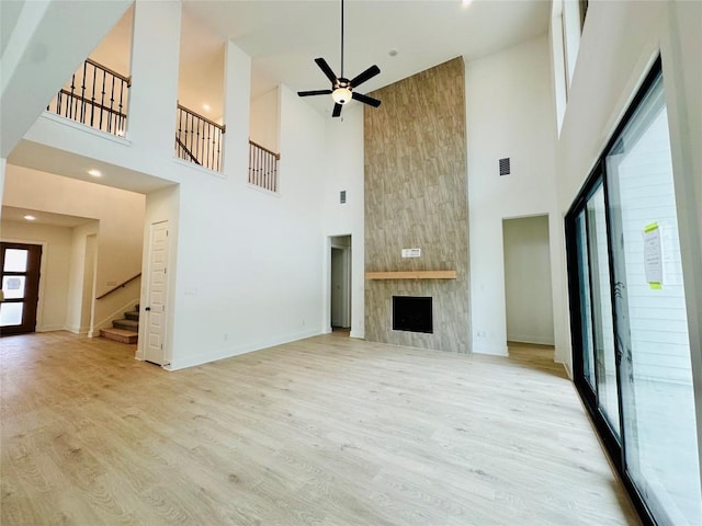 1670 Headwaters Blvd, Dripping Springs, TX 78620 - unfurnished living room featuring a high ceiling, stairs, wood finished floors, ceiling fan, and baseboards