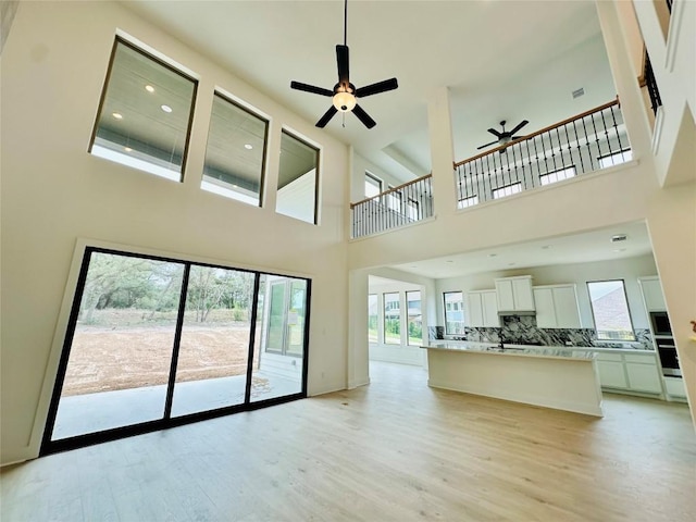 1670 Headwaters Blvd, Dripping Springs, TX 78620 - unfurnished living room featuring ceiling fan, a towering ceiling, light wood finished floors, healthy amount of natural light, and recessed lighting