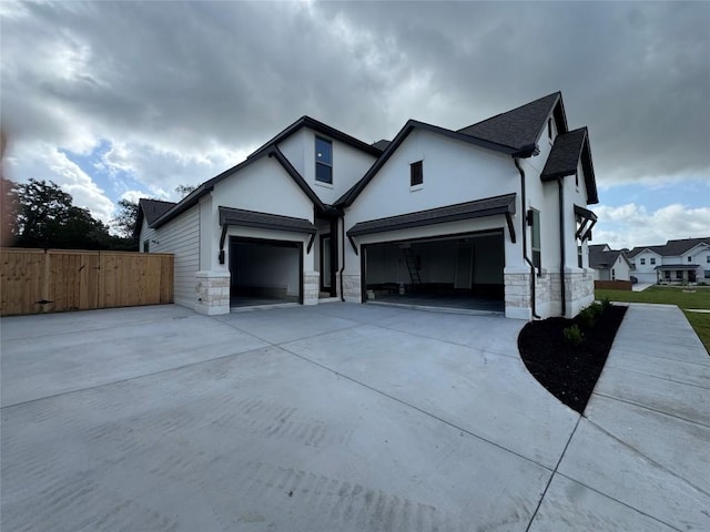 1670 Headwaters Blvd, Dripping Springs, TX 78620 - view of side of home with an attached garage, stone siding, concrete driveway, stucco siding, and roof with shingles