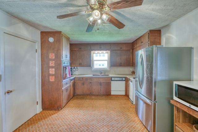 kitchen featuring a sink, white appliances, brown cabinetry, light countertops, and light floors