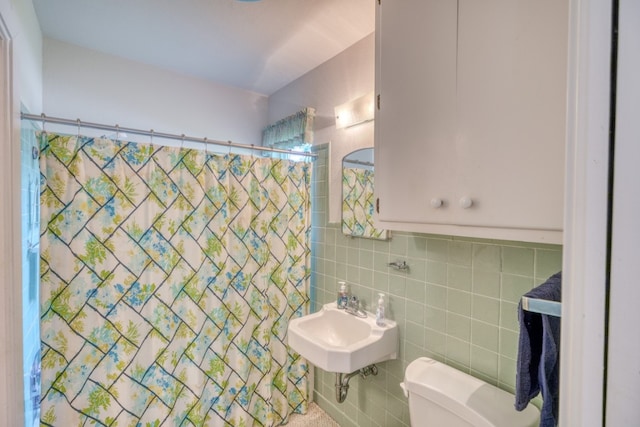 bathroom with a shower with curtain, tile walls, toilet, and a sink