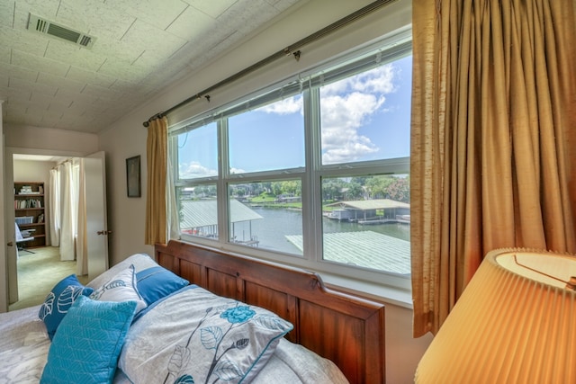 carpeted bedroom featuring visible vents and a water view