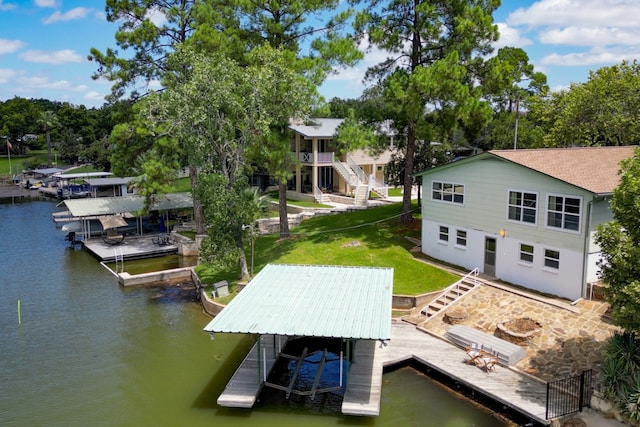 dock area with stairway, a water view, boat lift, and a lawn