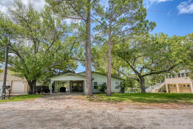 view of front facade with stairway, an attached carport, driveway, and a front lawn