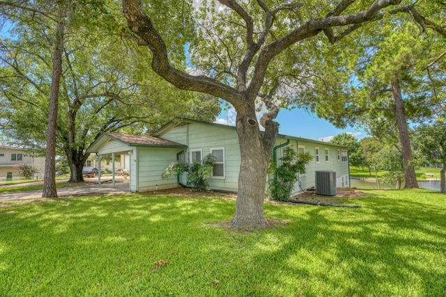 rear view of house with a lawn, central AC unit, and a carport