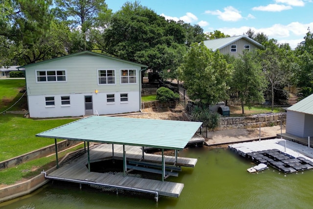 back of property with boat lift, a lawn, and a water view