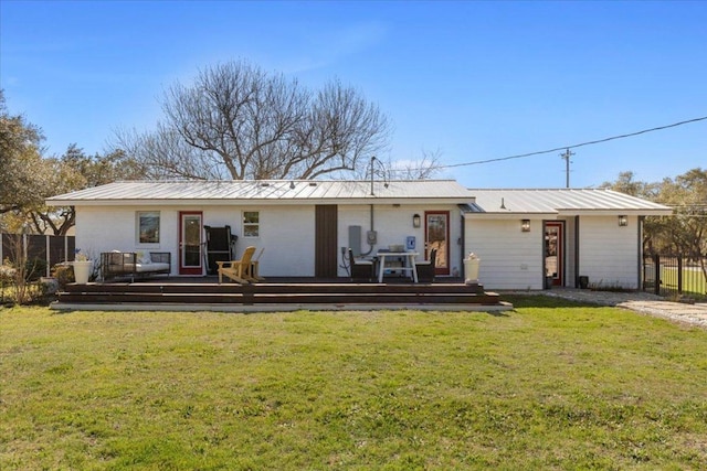 back of house with metal roof, a lawn, fence, and a wooden deck