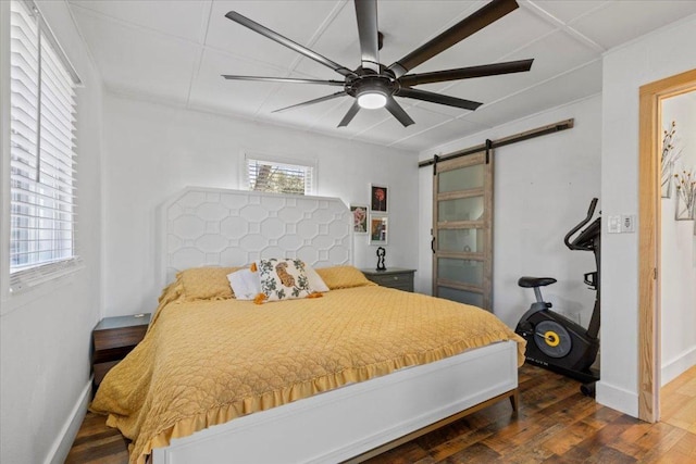 bedroom with a barn door, baseboards, wood finished floors, and a ceiling fan