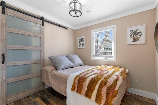 bedroom with dark wood finished floors, a barn door, and baseboards