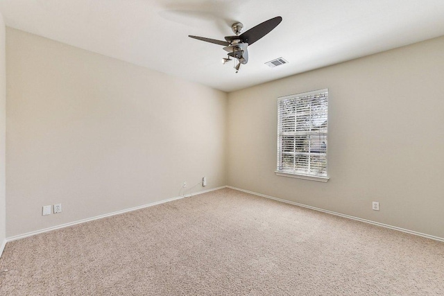 carpeted empty room with visible vents, baseboards, and ceiling fan