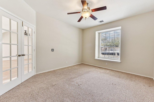 carpeted spare room with a ceiling fan, french doors, visible vents, and baseboards