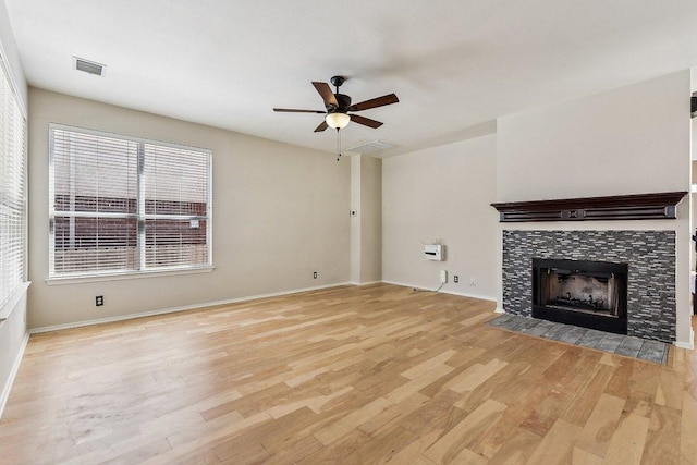 unfurnished living room featuring baseboards, visible vents, a fireplace, ceiling fan, and light wood-style floors