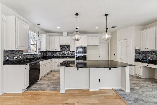 kitchen featuring visible vents, black appliances, a sink, a kitchen island, and white cabinetry