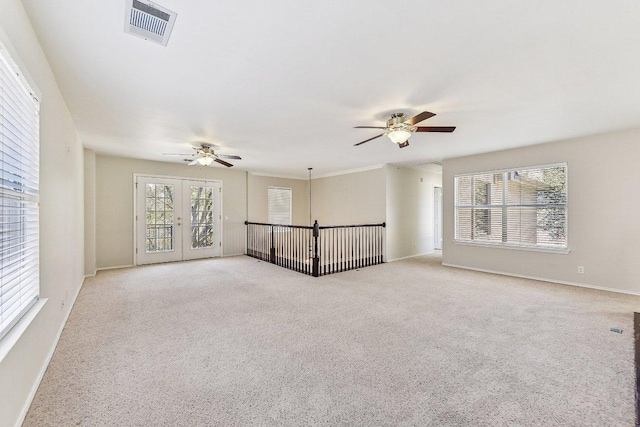 empty room with baseboards, light colored carpet, visible vents, and ceiling fan