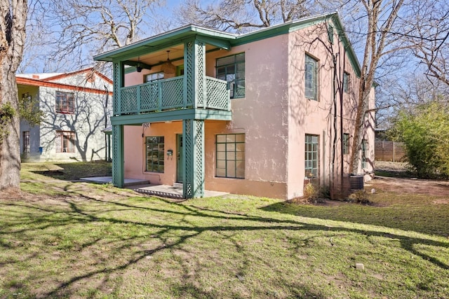 back of house with a patio, a balcony, a lawn, and stucco siding