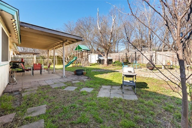 view of yard featuring a patio area, a playground, and a fenced backyard