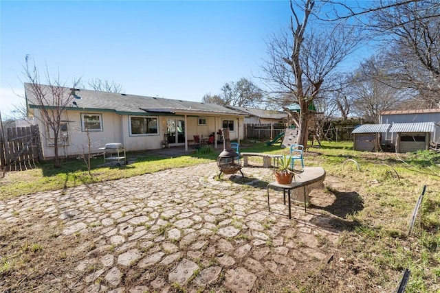 rear view of house featuring a patio, a fenced backyard, and a fire pit