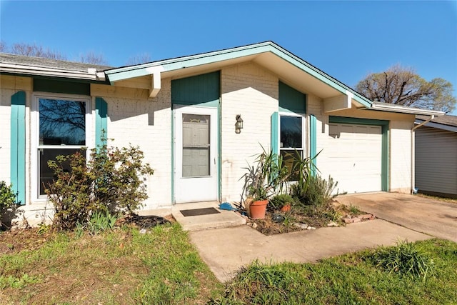 property entrance featuring a garage, brick siding, and concrete driveway