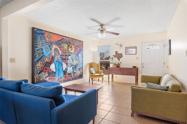 living area featuring light tile patterned flooring, a ceiling fan, and a textured ceiling