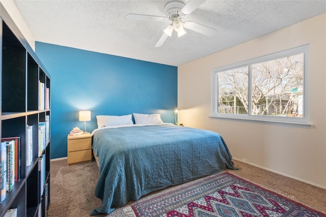 carpeted bedroom featuring ceiling fan, baseboards, and a textured ceiling