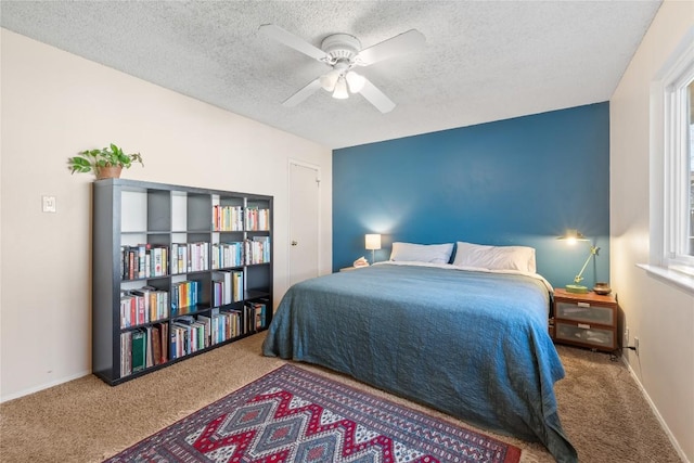 carpeted bedroom with ceiling fan, baseboards, and a textured ceiling