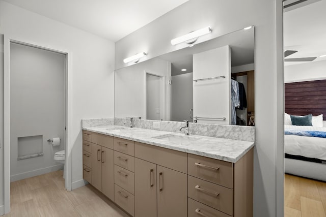 ensuite bathroom featuring double vanity, connected bathroom, toilet, and a sink