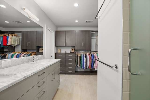 bathroom with a sink, visible vents, double vanity, and recessed lighting