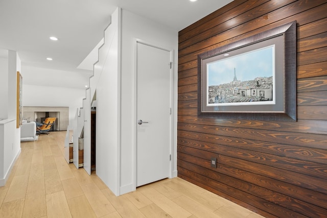 hallway featuring recessed lighting, light wood-style flooring, and wood walls