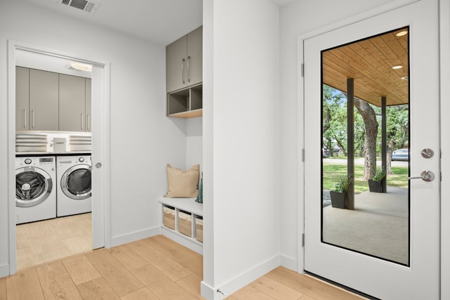 washroom with visible vents, washer and dryer, cabinet space, light wood finished floors, and baseboards