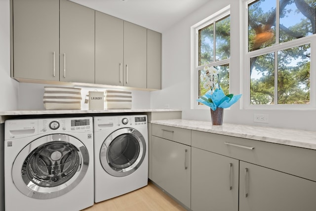 washroom with washing machine and clothes dryer, cabinet space, and light wood-style floors